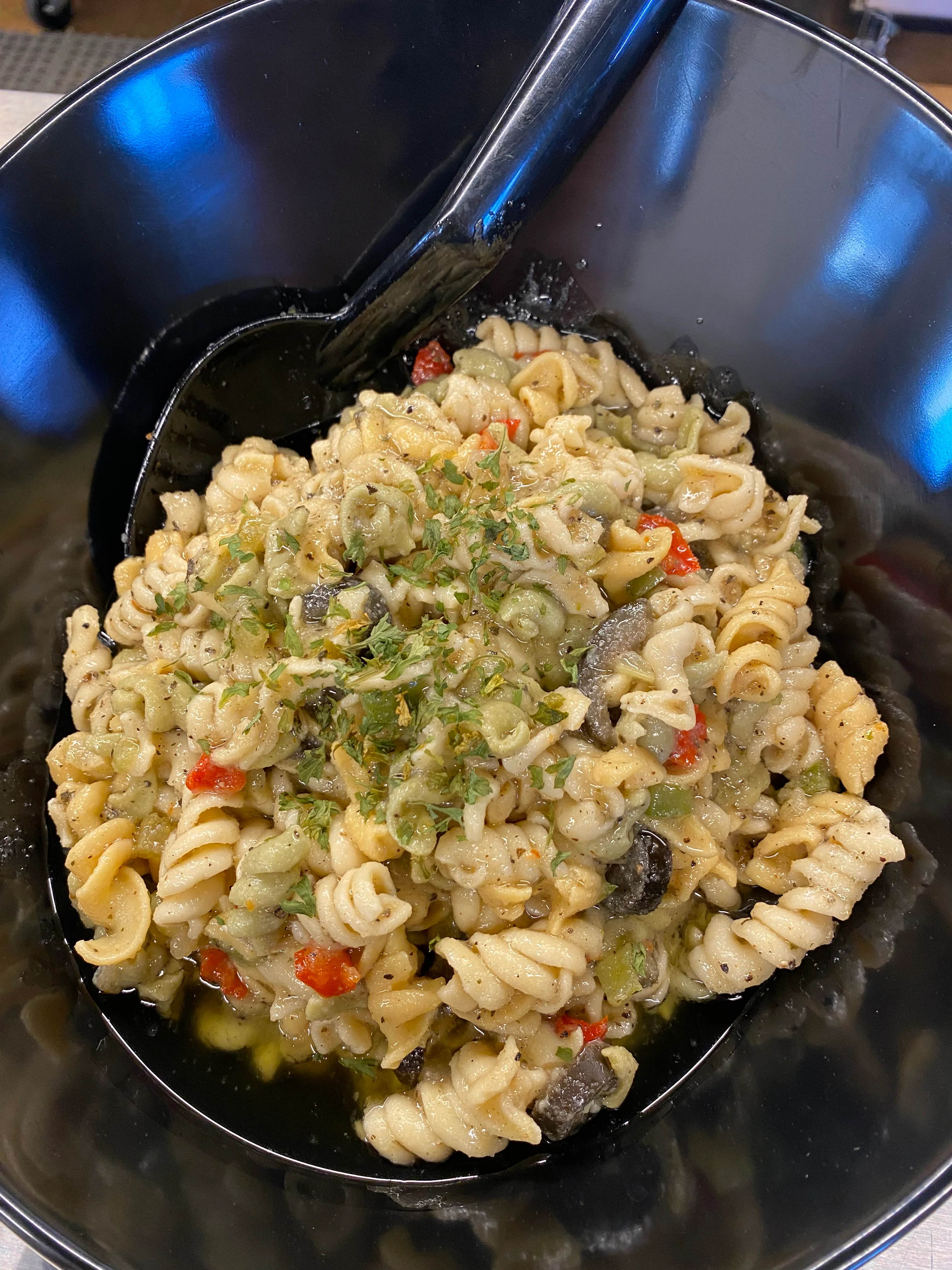Italian pasta primavera with vegetables in a black bowl