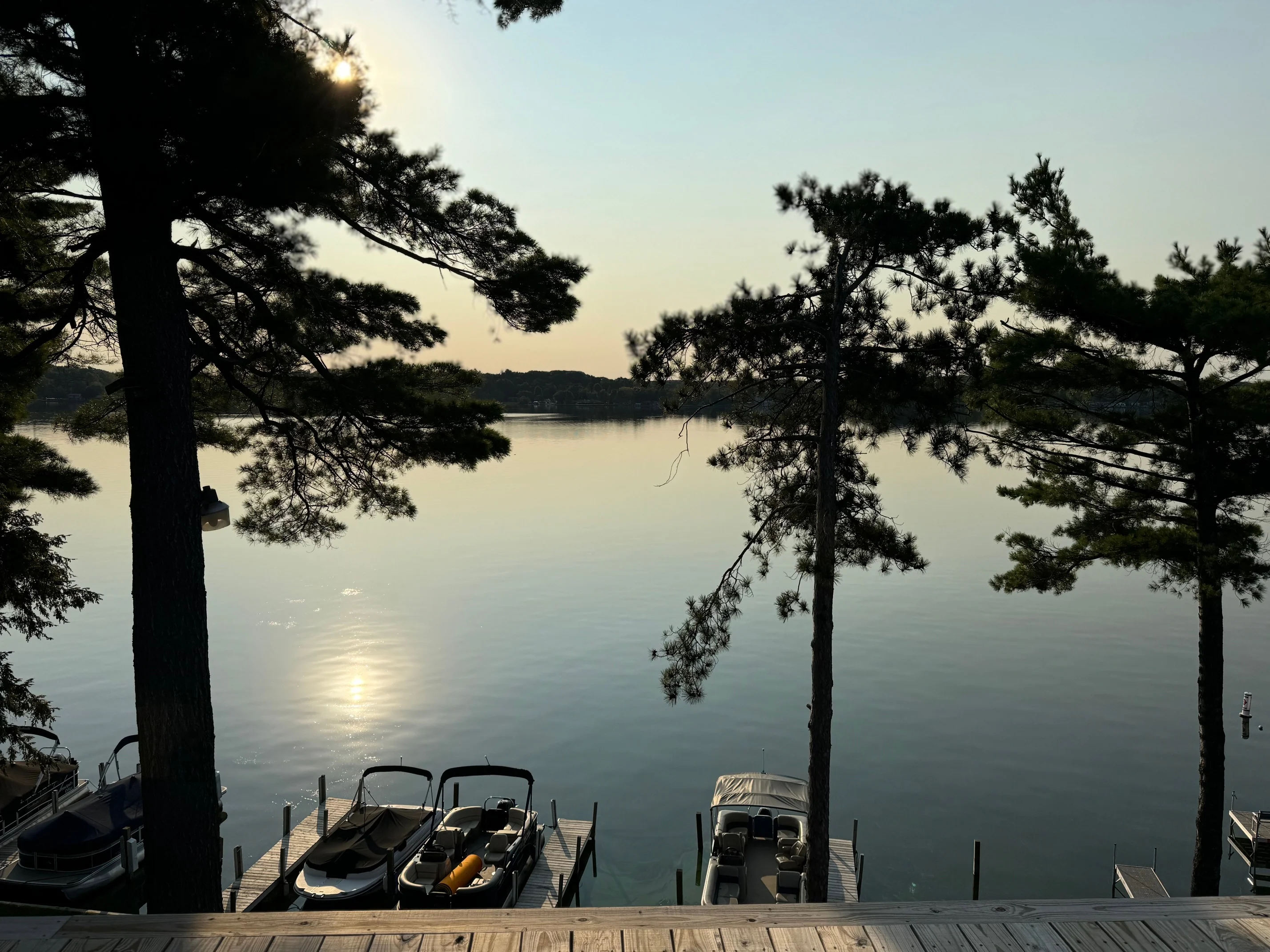 Scenic lakeside view with boats and trees at sunset