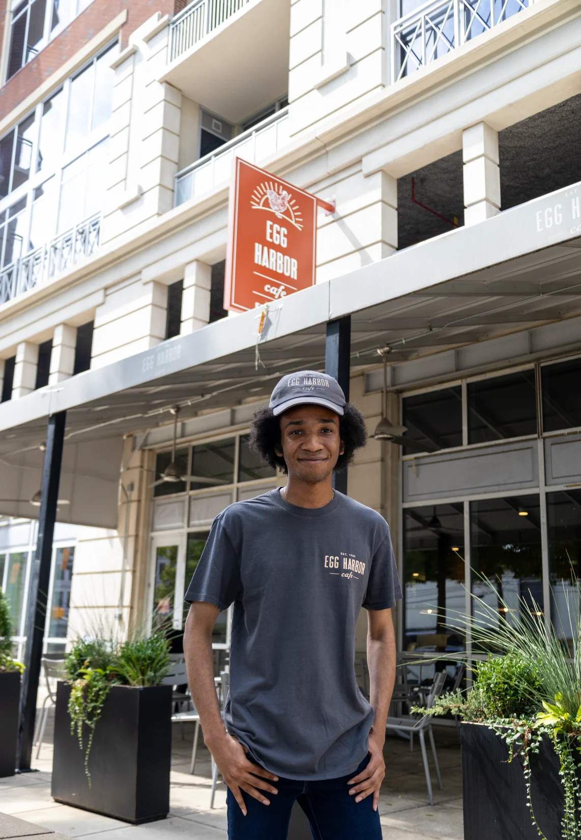 Employee in front of Egg Harbor Cafe, showcasing the restaurant's branding