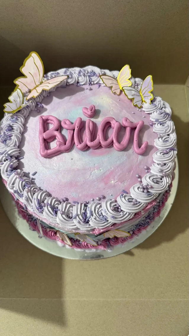 Decorative birthday cake with purple frosting and butterfly accents