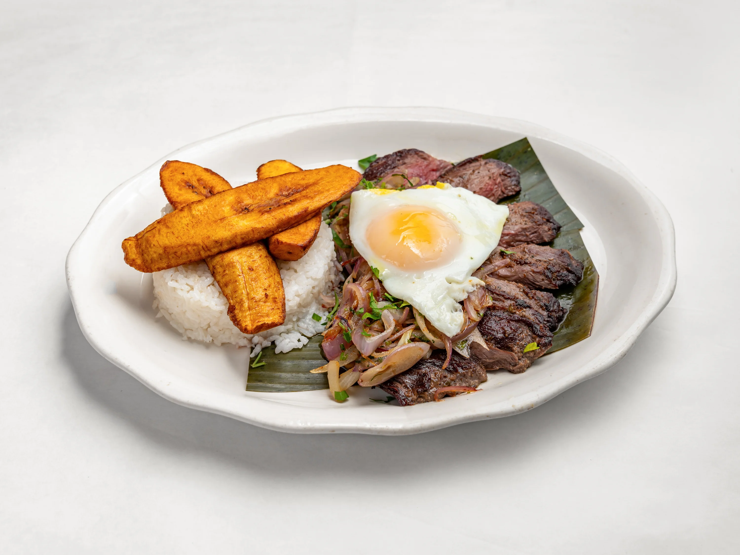 churrasquito, Skirt Steak topped with caramelized onions and fried egg, served with rice sweet plantains and beans