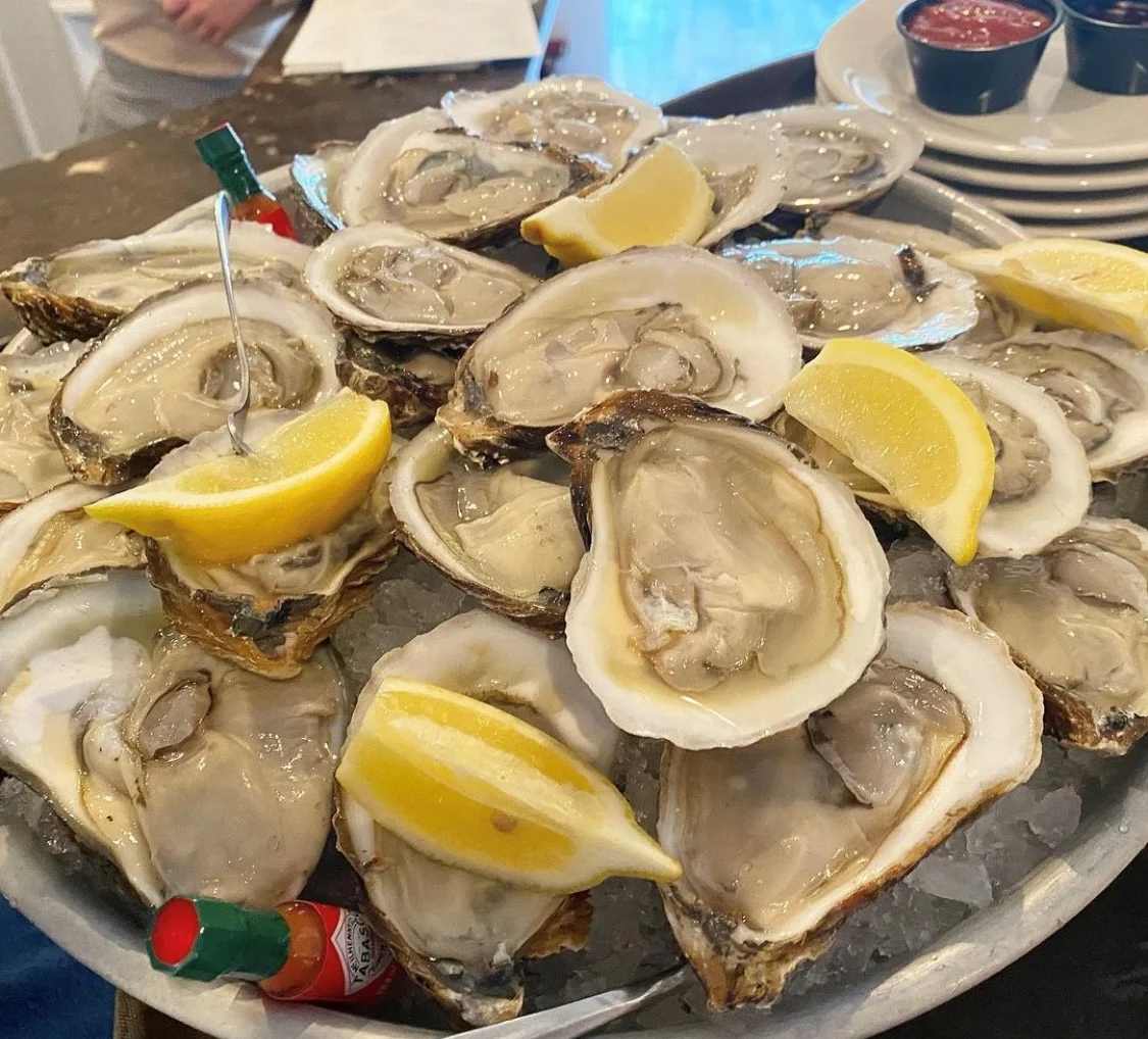 Fresh oysters served on ice with lemon wedges and garnishes.