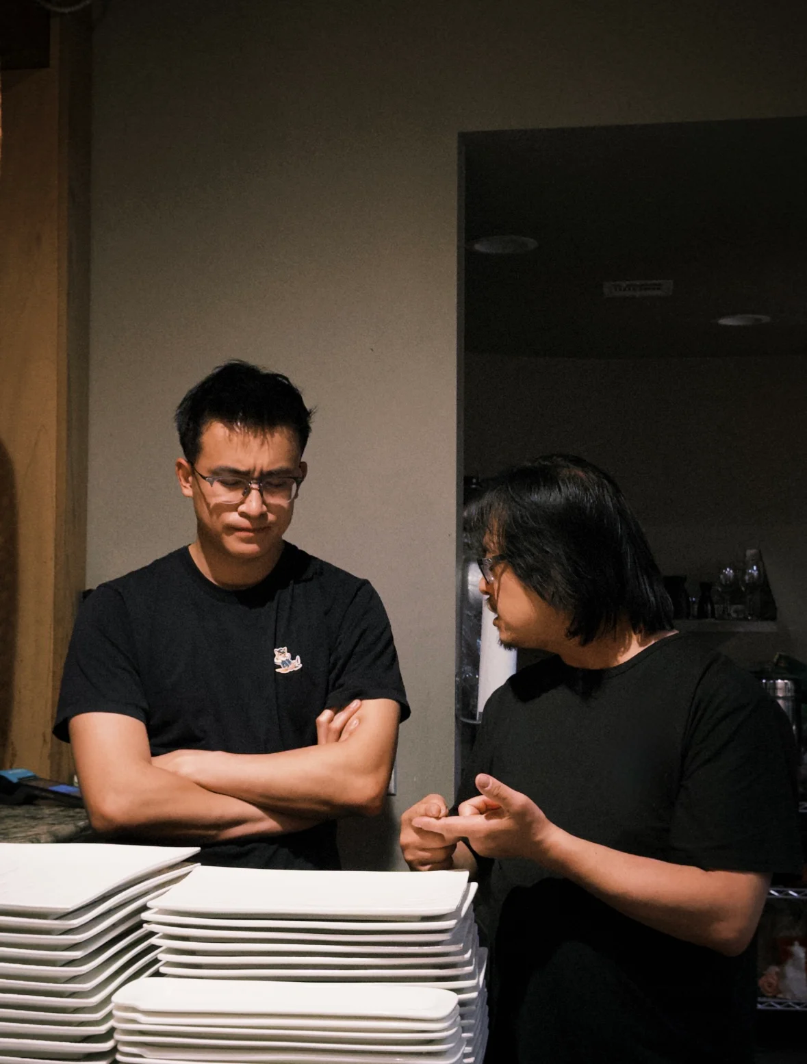 Two restaurant staff discussing near stacked plates