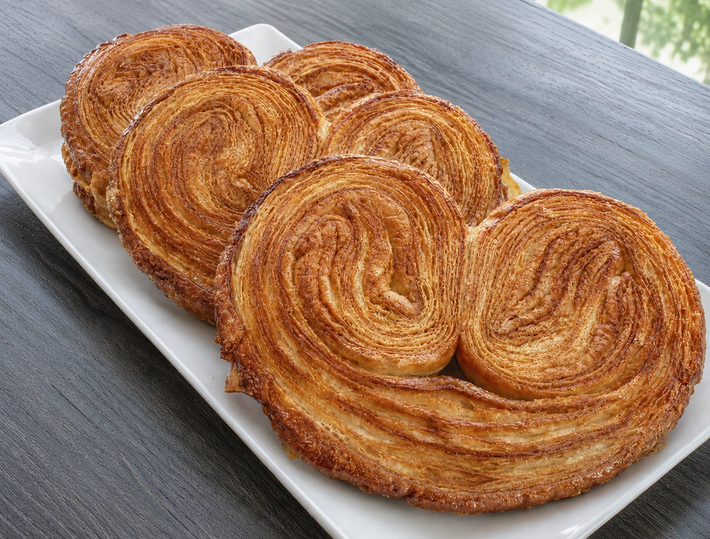 Freshly baked palmier pastries arranged on a white platter.