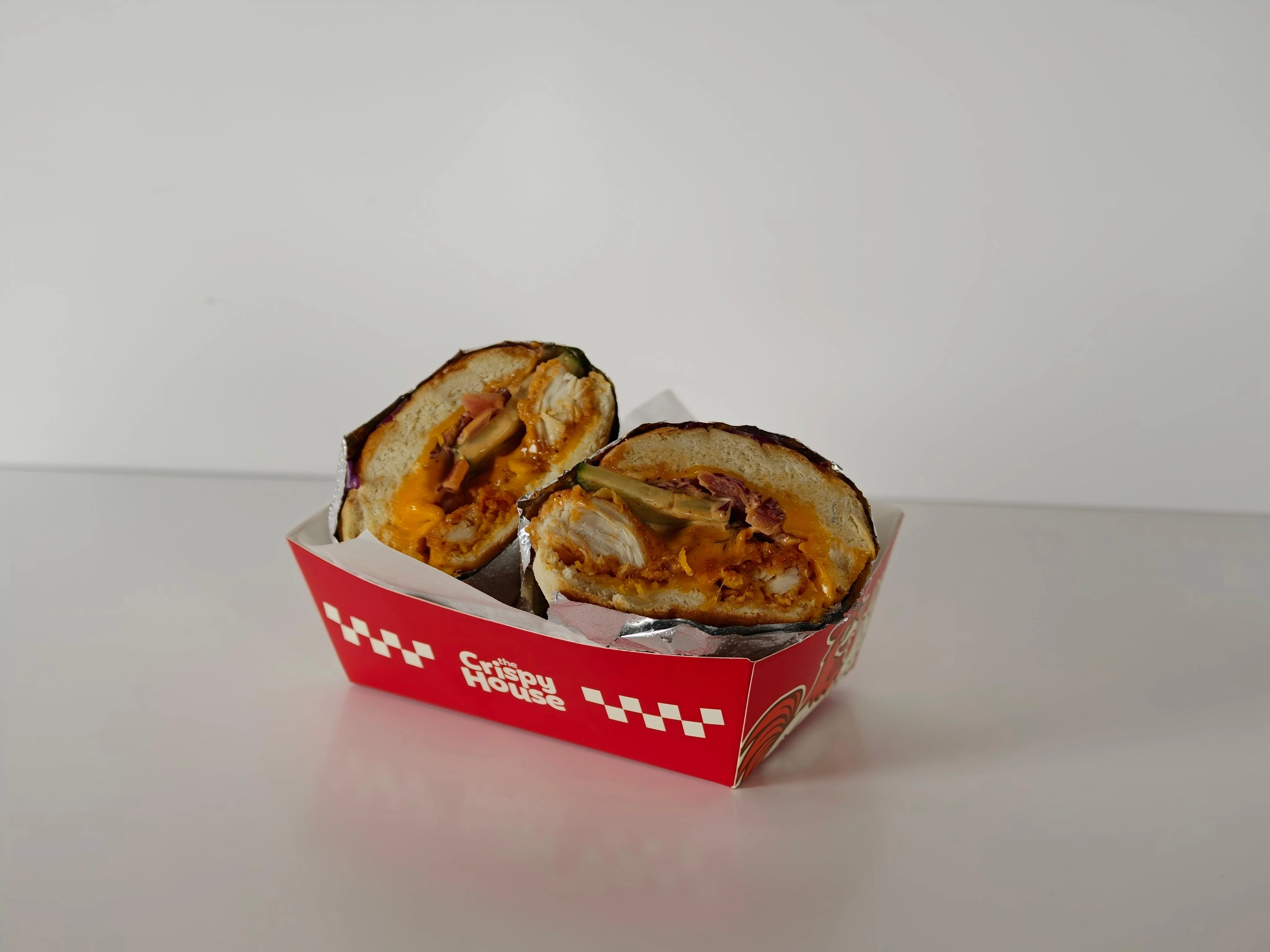 A halved wrap featuring various fillings, served in a red container with a logo. The wrap reveals layers of ingredients inside.