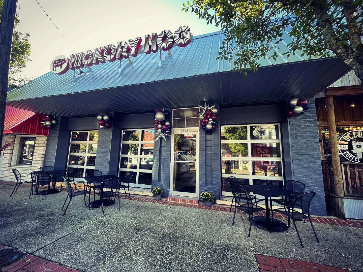 The exterior of a restaurant named 'Hickory Hog' featuring a decorative facade with outdoor seating and festive decorations.