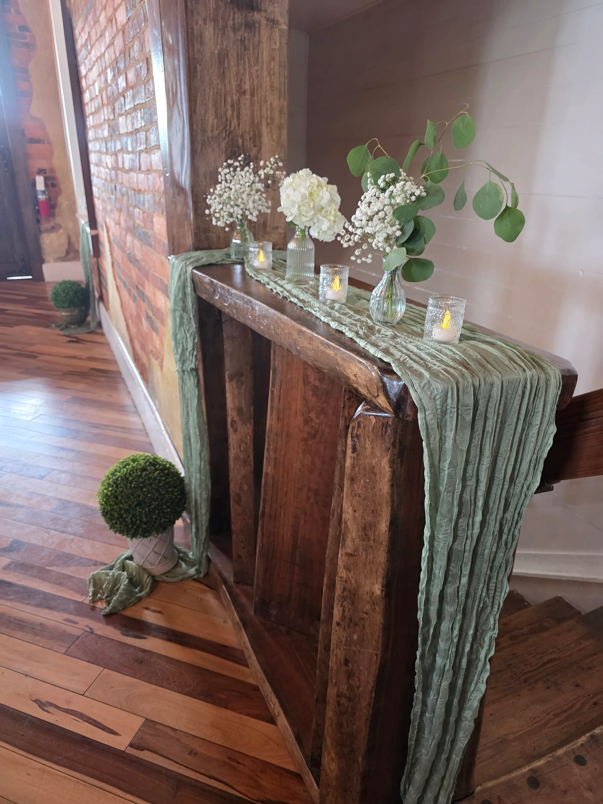 A rustic wooden table adorned with vases of flowers and candles, creating an inviting decor setup in a warm interior.