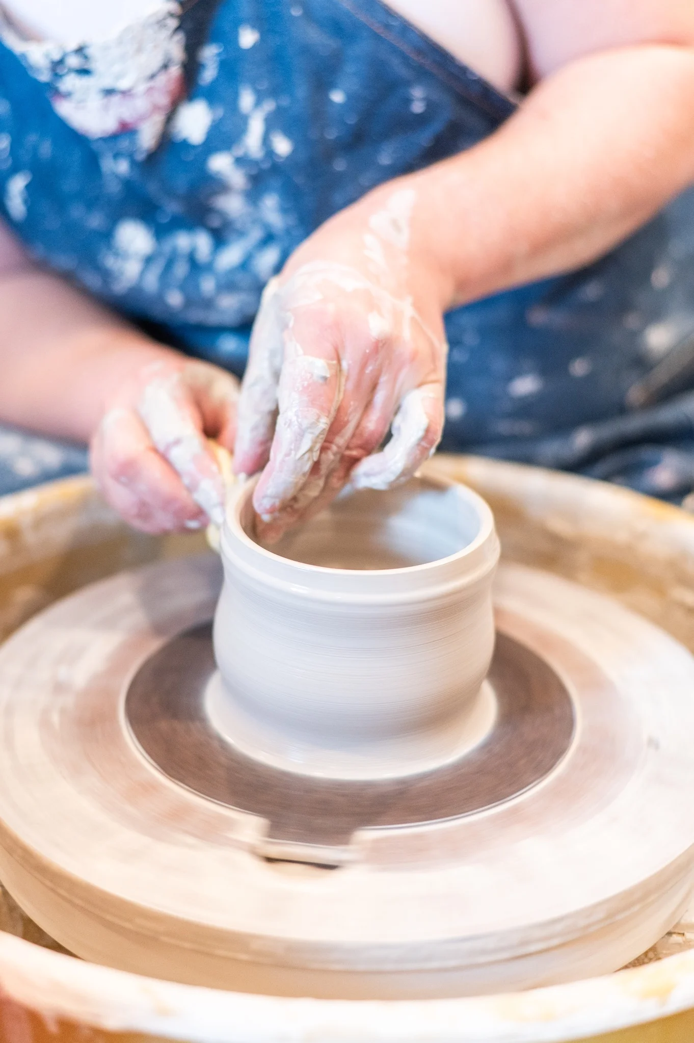 Potter shaping clay on a wheel in a studio