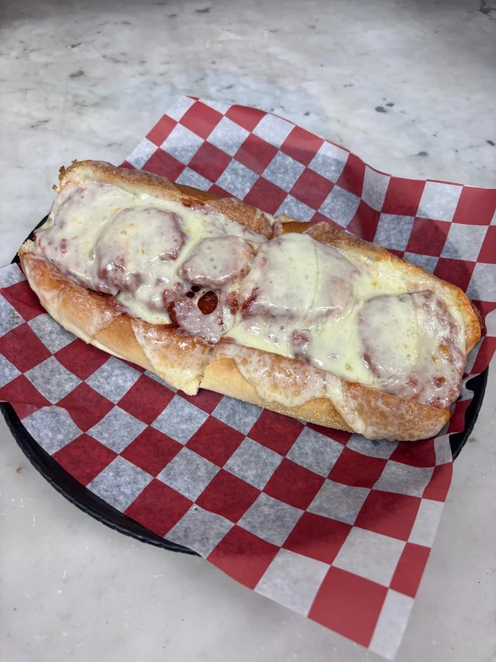Pasquale’s hot sub topped with tomato sauce and melted cheese
