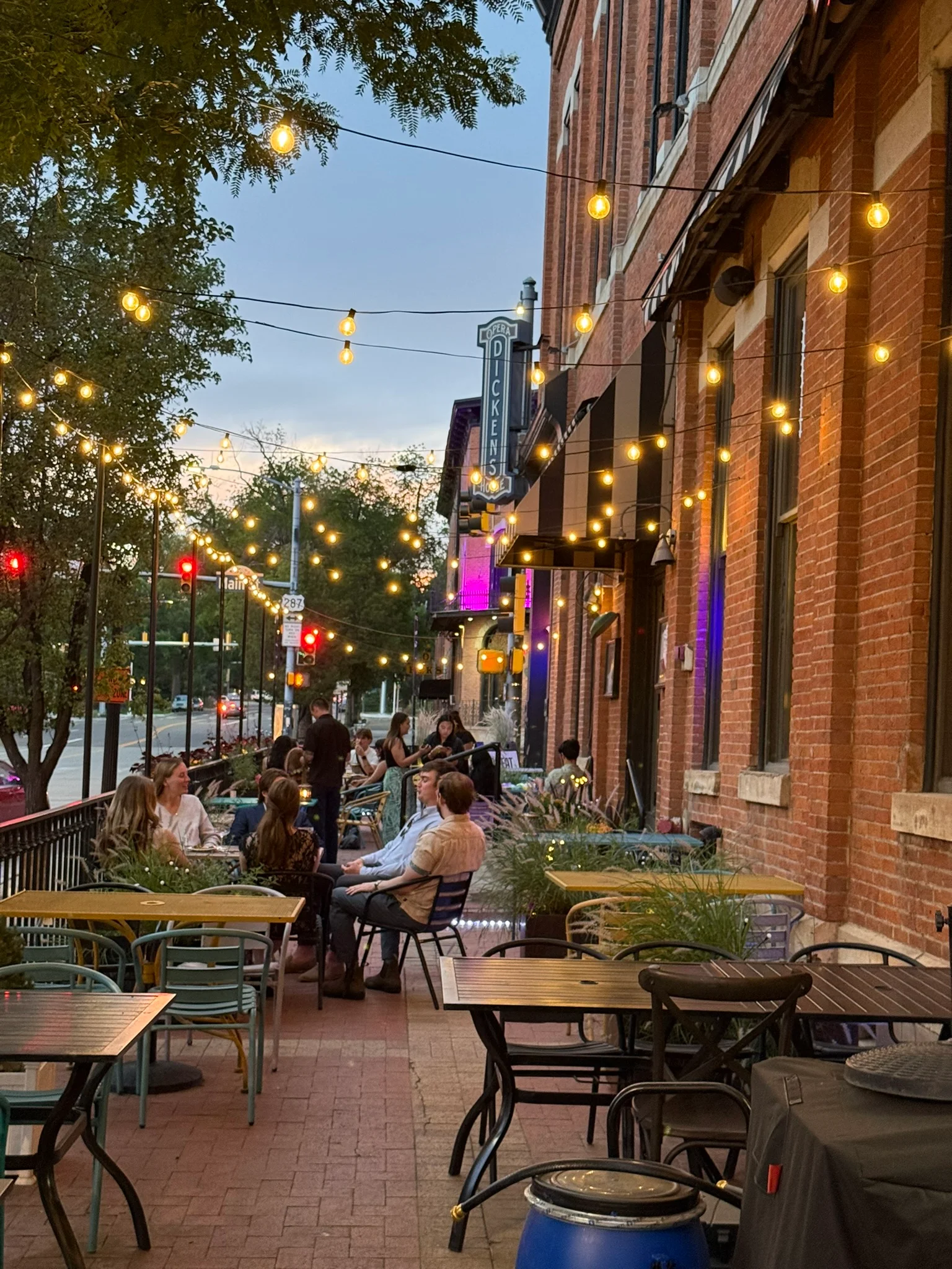 Lively restaurant patio with string lights beside a historic brick building