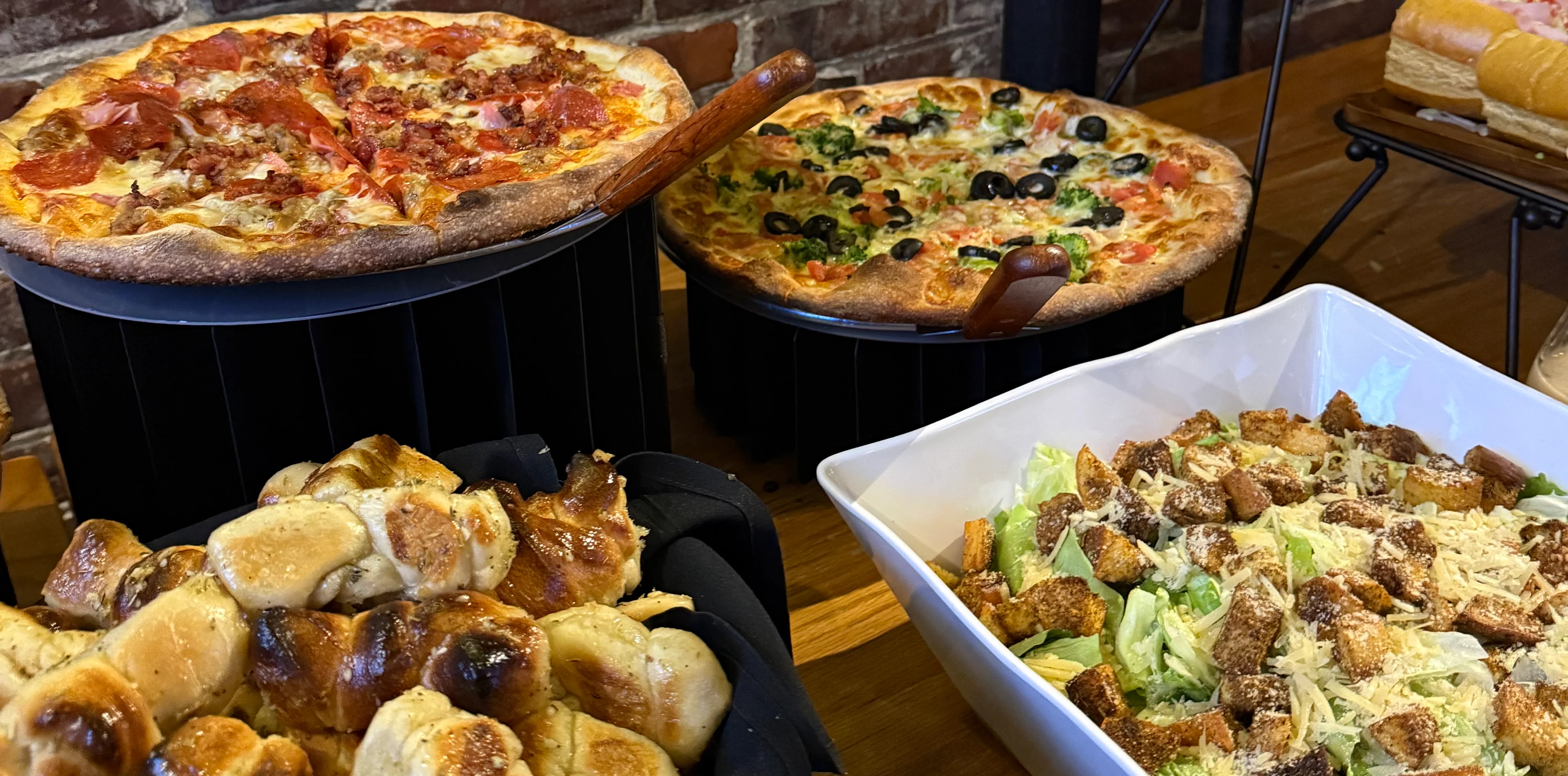 Buffet of pizza, garlic knots, and Caesar salad from an event hosted at Giovani's Bar and Grill