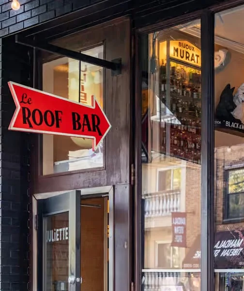 Exterior view of Le Roof Bar with a red directional sign