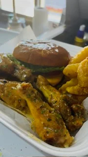 A cheeseburger featuring a grilled beef patty topped with melted cheese, lettuce, and tomato, all nestled in a sesame seed bun.