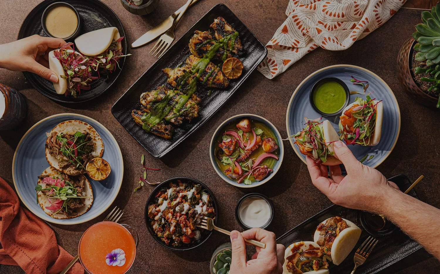 Assorted Mexican tacos and bao buns served in a vibrant restaurant setting
