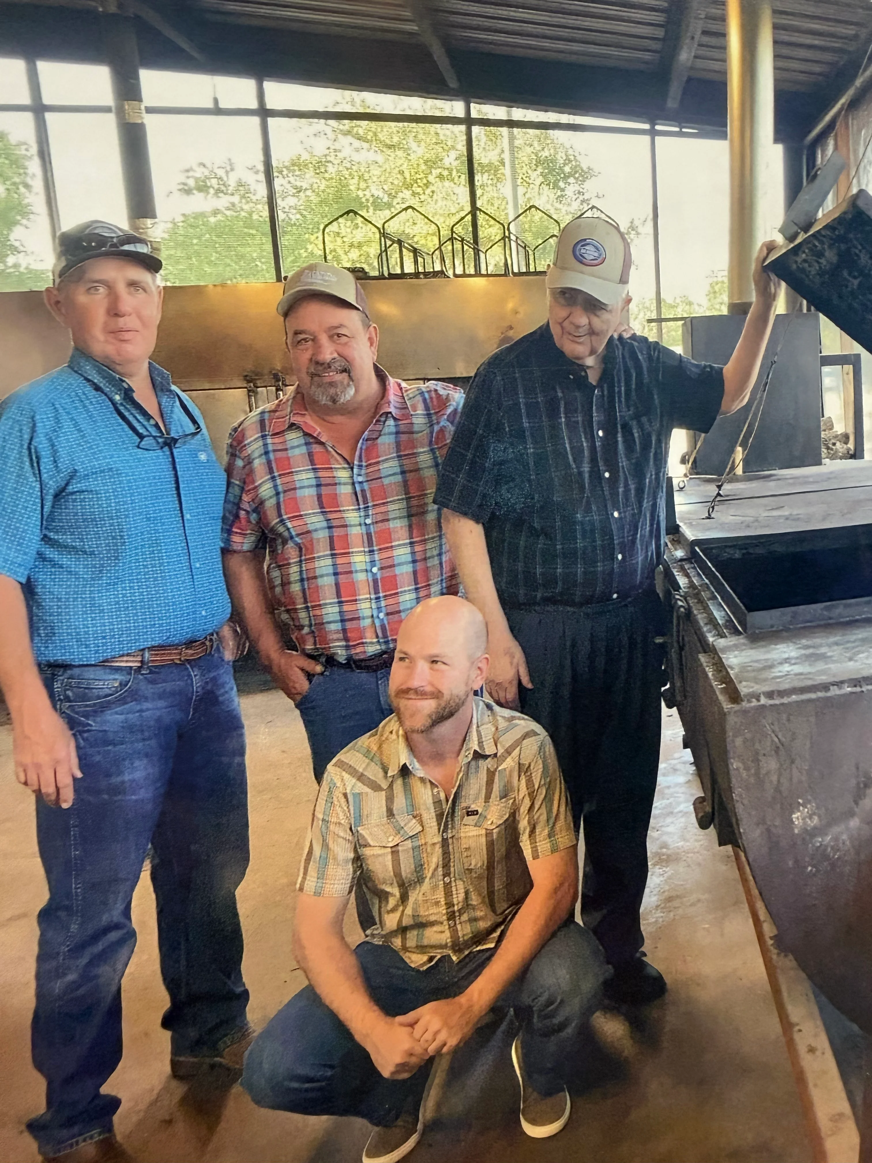 Group of men posing near a barbecue pit in a rustic setting