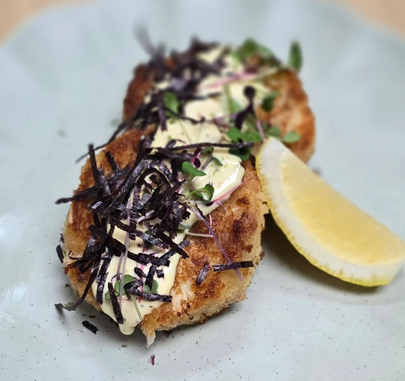 Japanese croquette with creamy sauce and seaweed garnish