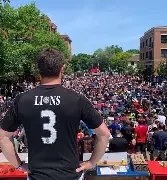 A lively crowd in a bar cheering enthusiastically, with hands raised in celebration. The atmosphere is filled with excitement and camaraderie.