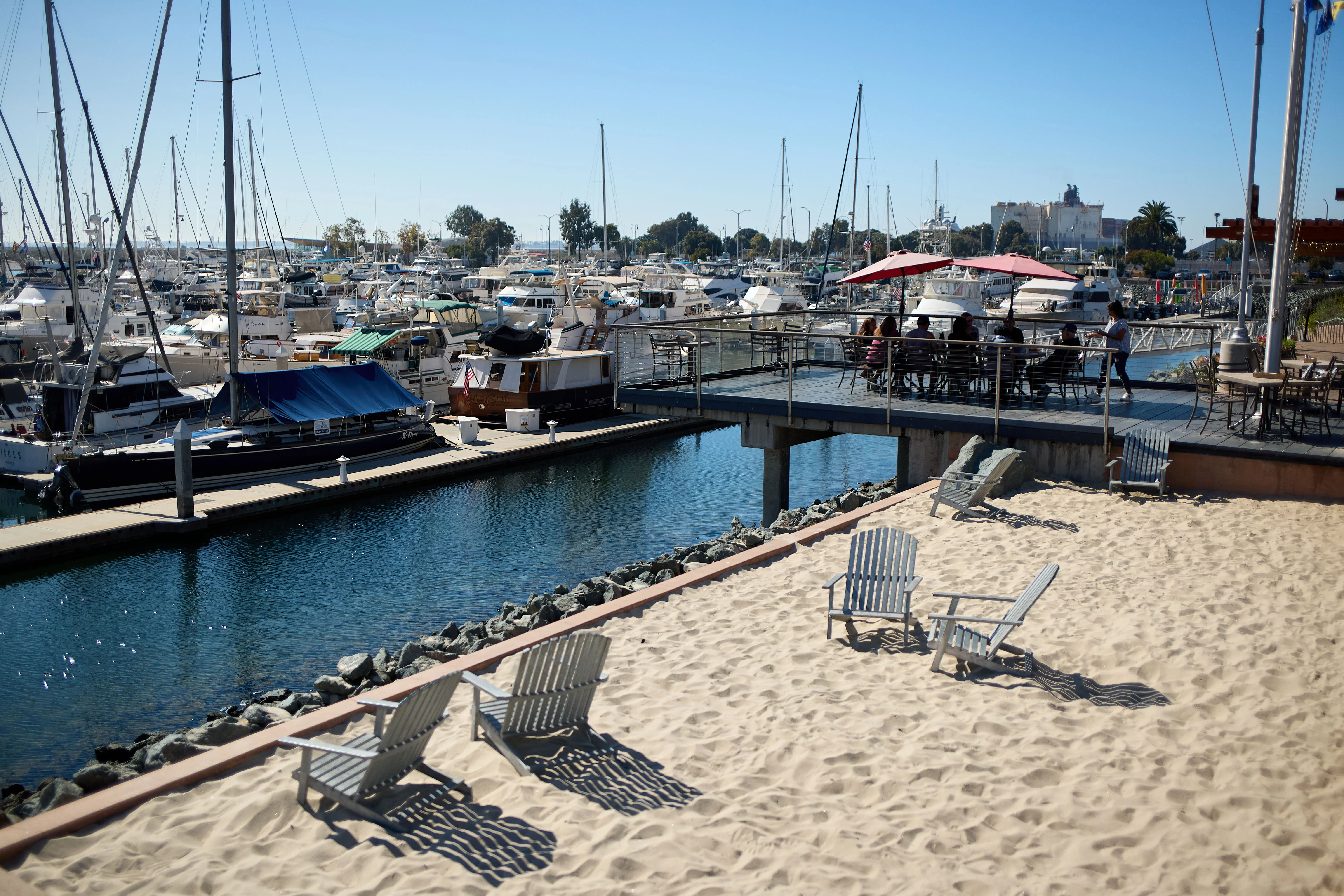 Scenic marina view with boats and sandy beach chairs