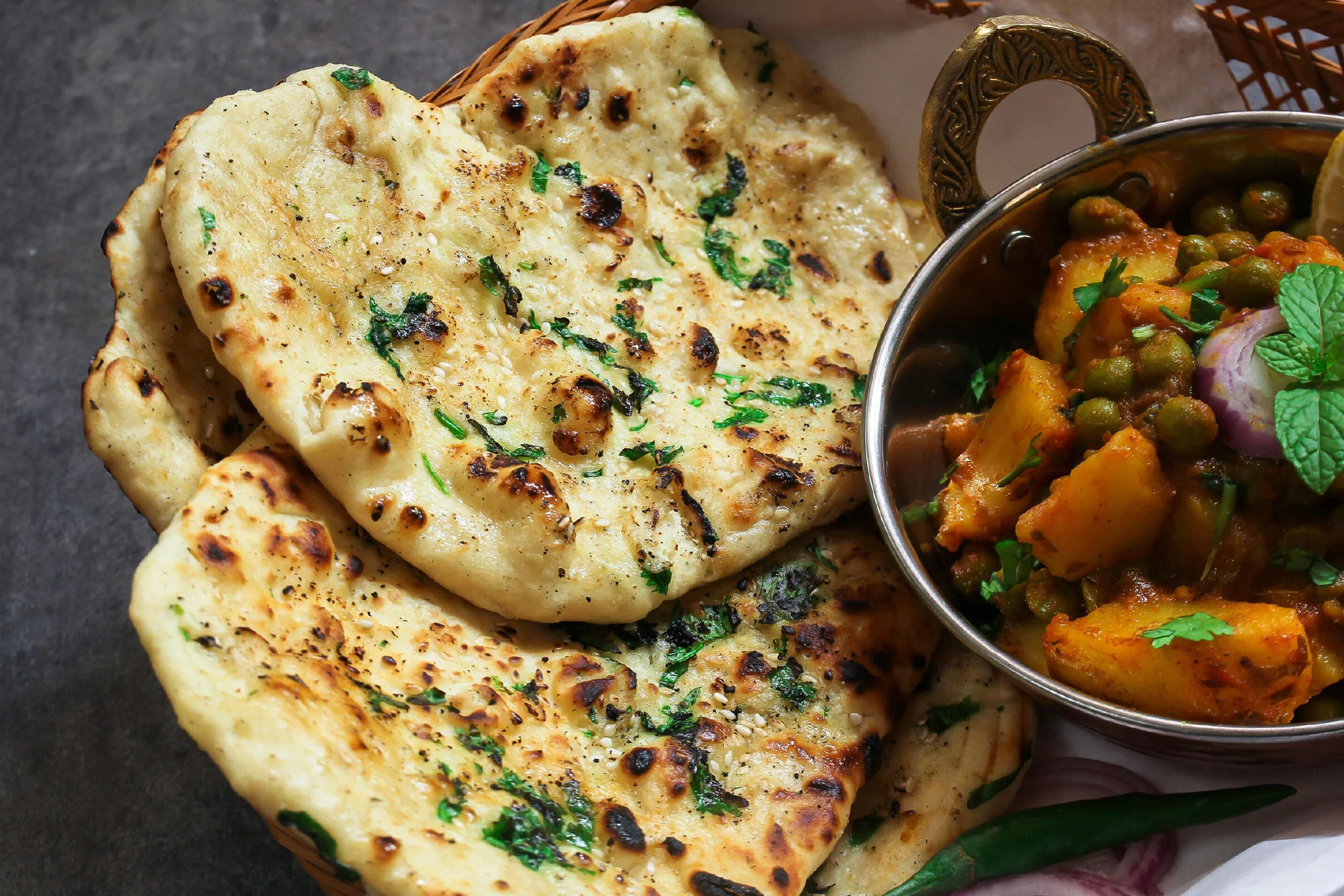 Freshly baked garlic naan bread on a wooden surface.