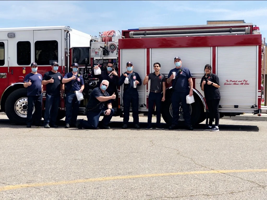 Firefighters posing with a fire truck, celebrating teamwork and community spirit