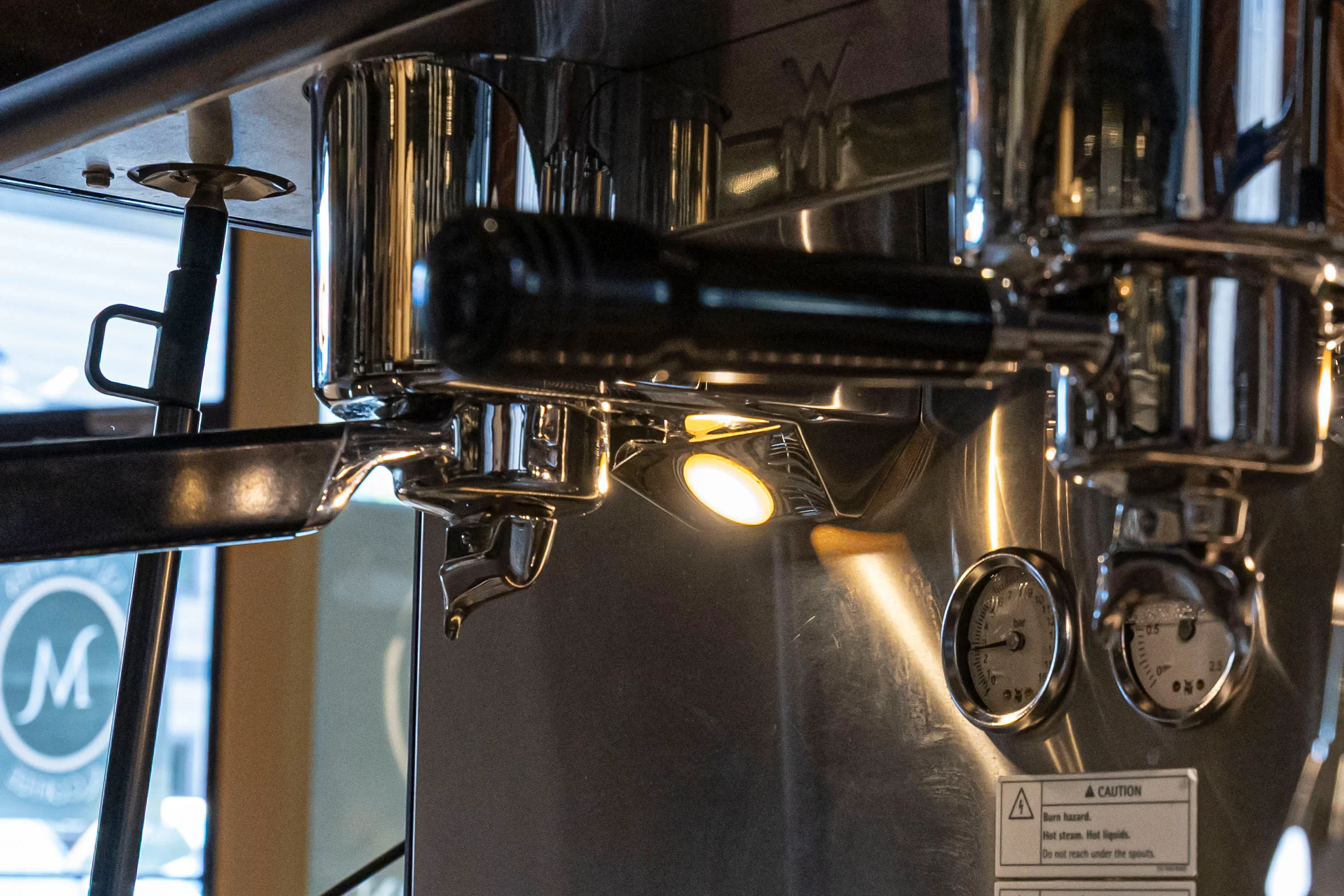 Close-up of a professional espresso machine's portafilter and gauges