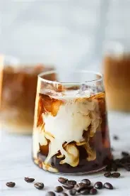 Iced coffee with cream swirling in a glass