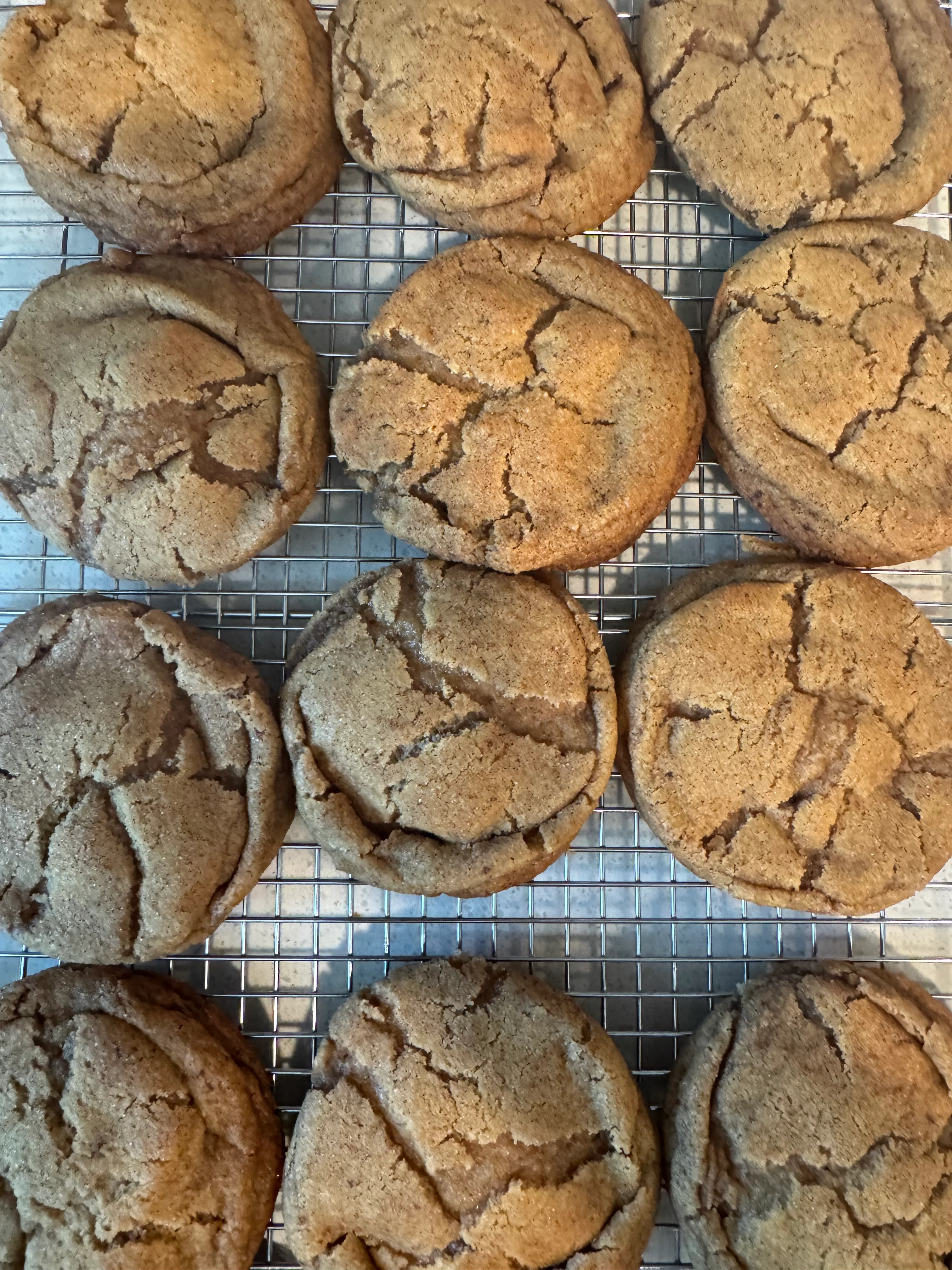 Smiling person holding a freshly baked cookie in a modern kitchen