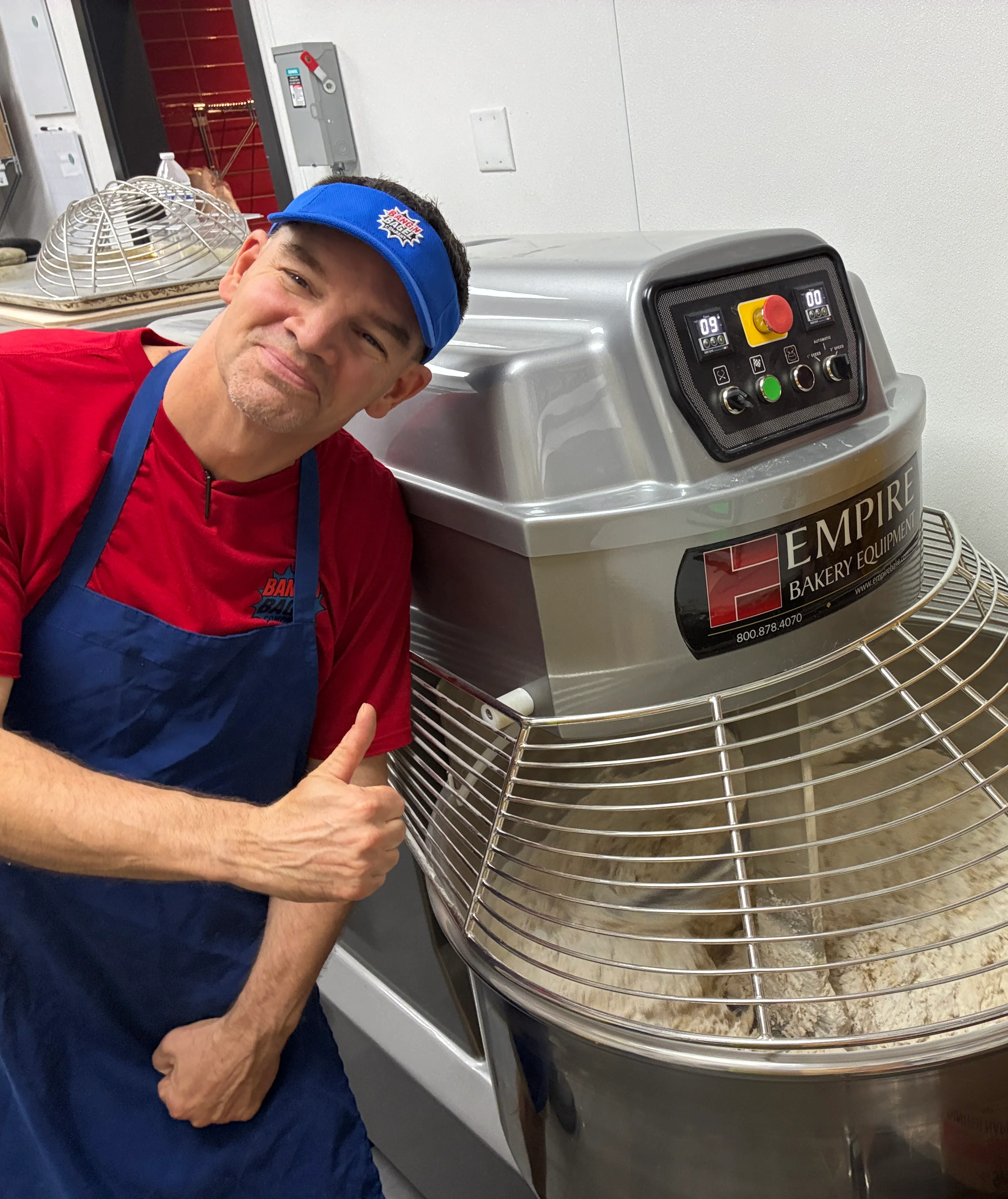 Bakers posing with a large dough mixer in a bakery
