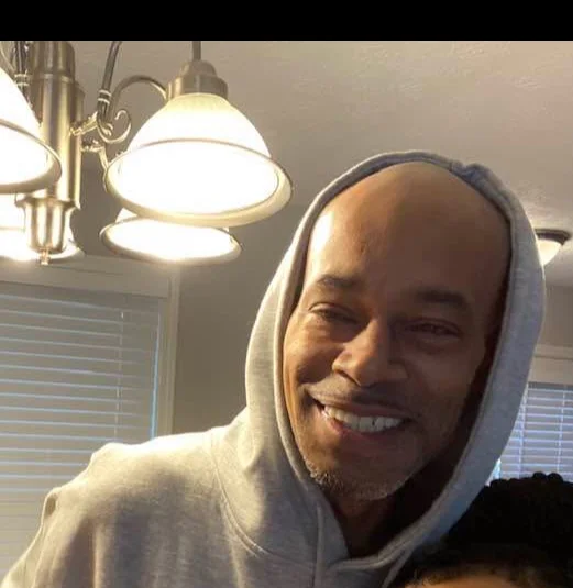 Smiling man in a hoodie with warm lighting in a cozy interior