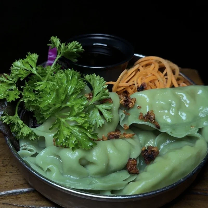 Colorful Tibetan momos served with dipping sauce and garnishes