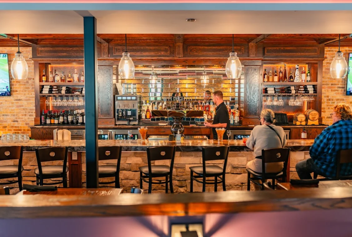 Bartender serving drinks at a stylish bar with warm lighting