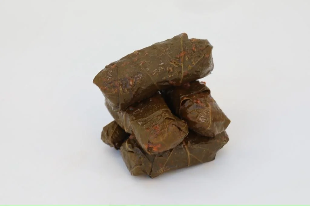 A stack of grape leaves stuffed with rice and spices, neatly arranged.