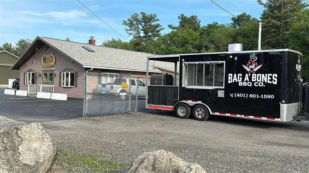 BBQ food truck parked outside a restaurant