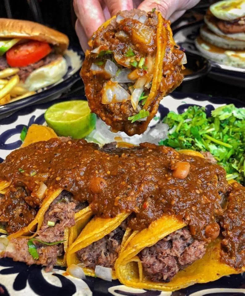 Authentic Mexican tacos topped with rich sauce and fresh herbs