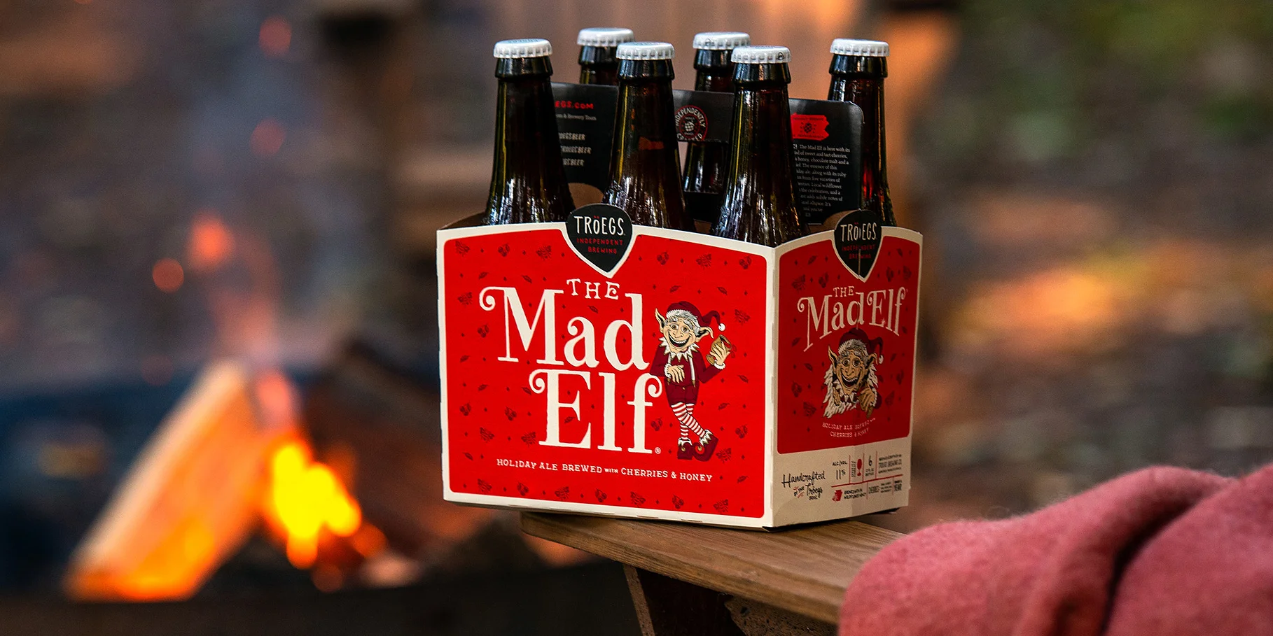 Pack of Troegs Mad Elf holiday ale by a campfire