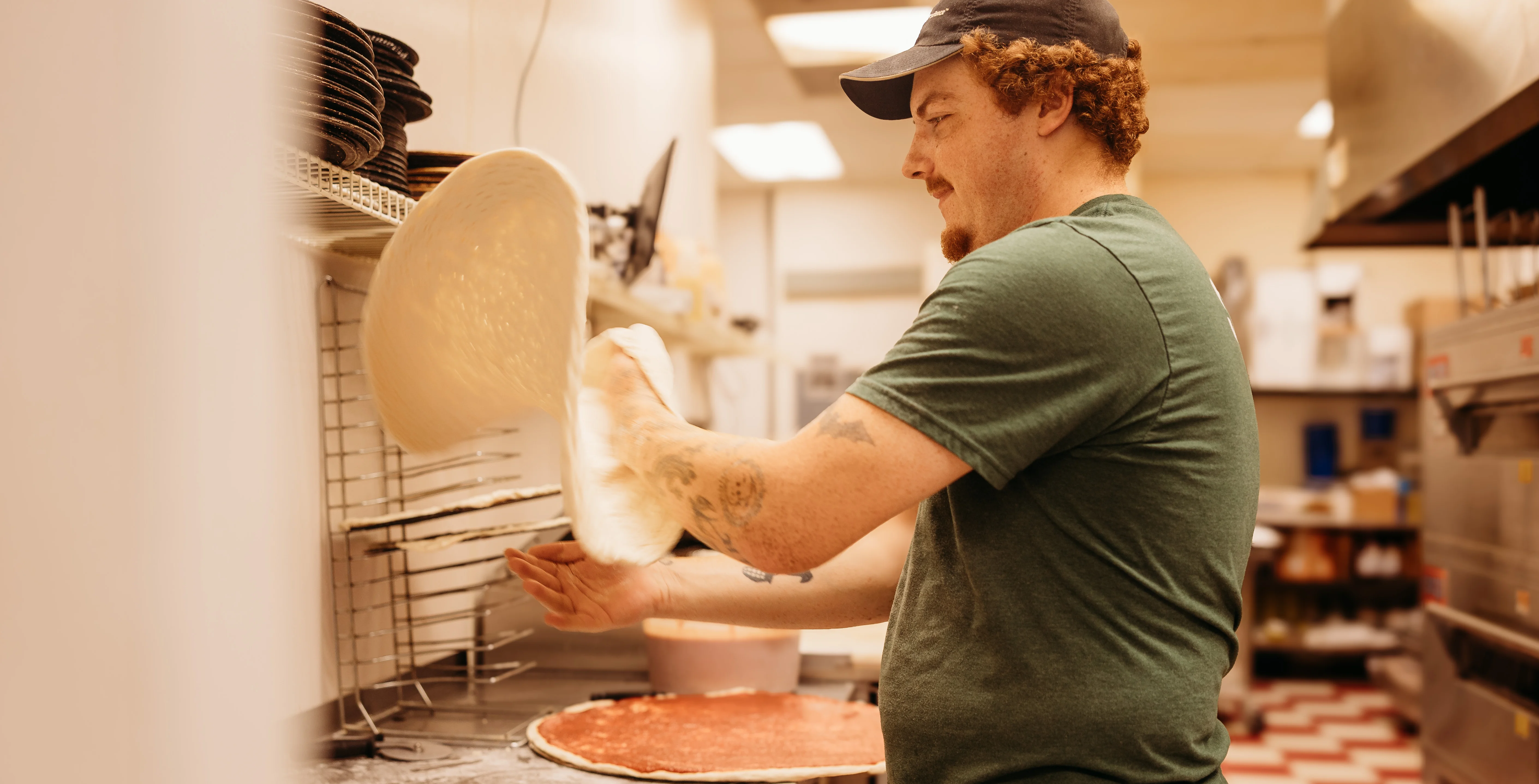 Pizza dough being tossed by a chef in a restaurant kitchen