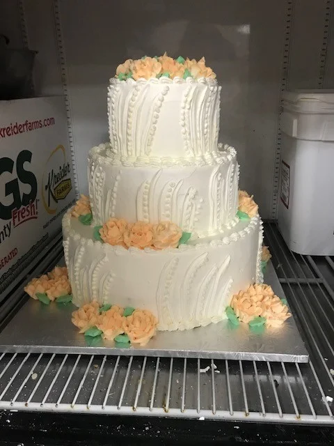 Three-tier white cake with peach piped flowers from The Kosher Pastry Oven