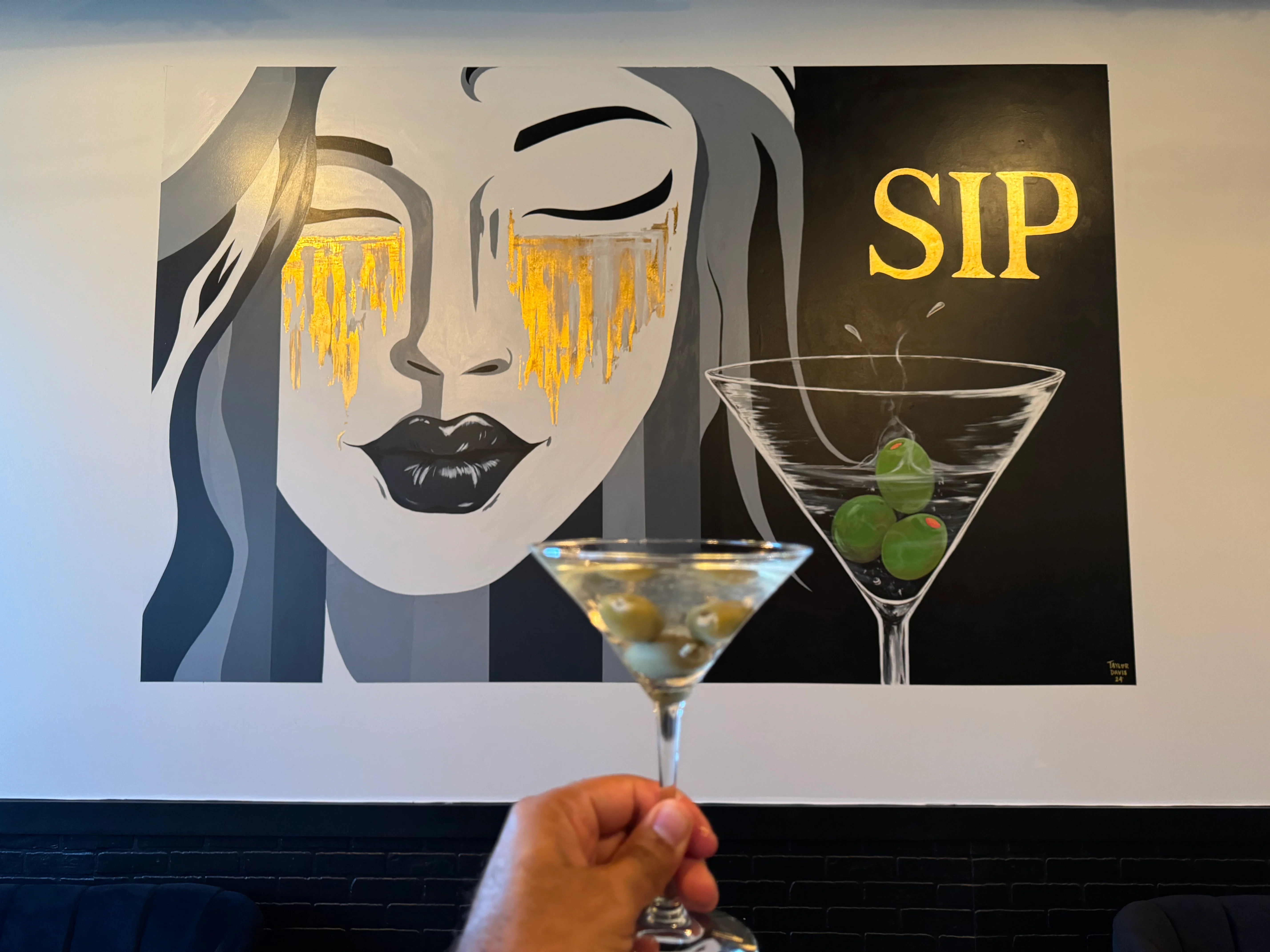 Cocktail in front of a stylish mural with the word 'SIP'