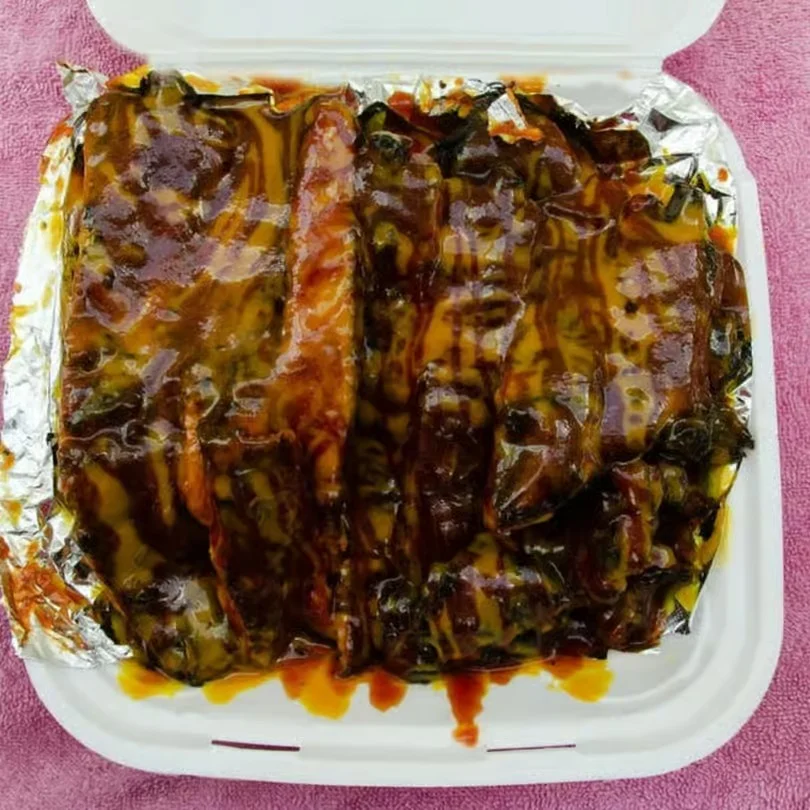 Delicious glazed ribs served in a takeout container.