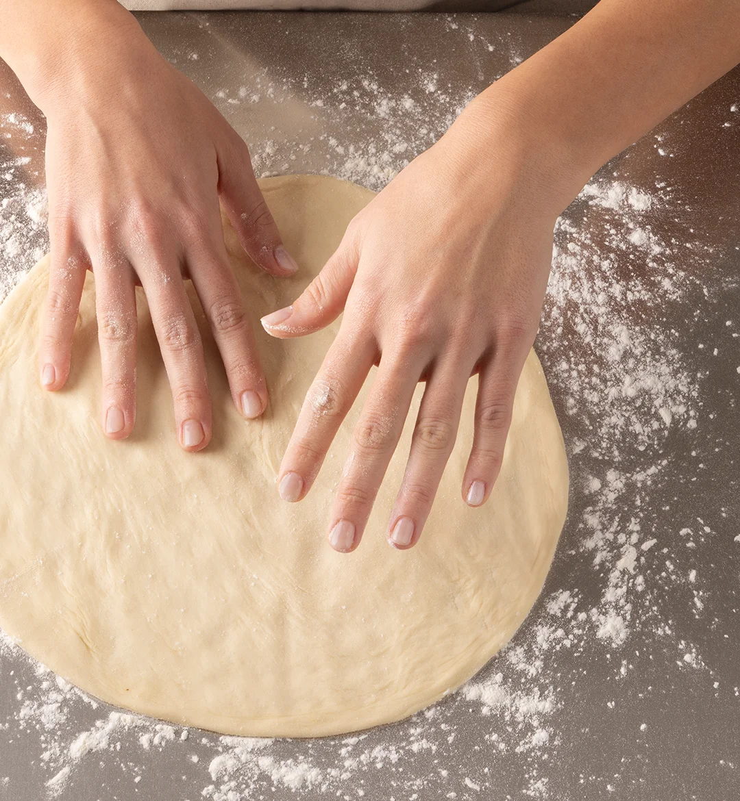 Rolling pizza dough on a floured surface
