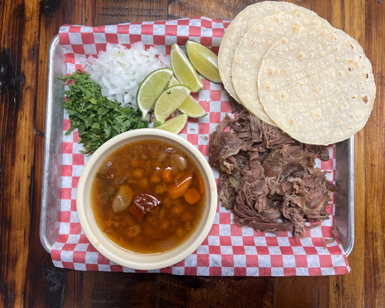 Traditional Mexican birria with tortillas and lime