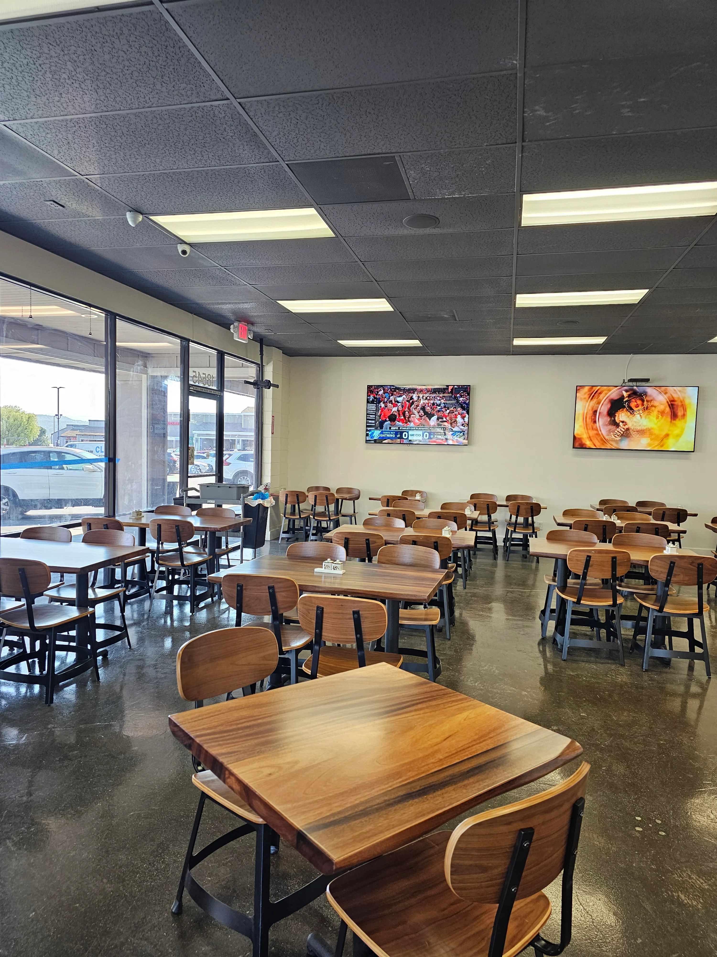 Modern restaurant interior with wooden tables and TVs