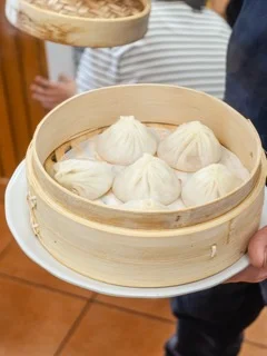 Steamed Xiaolongbao dumplings served in a bamboo basket.