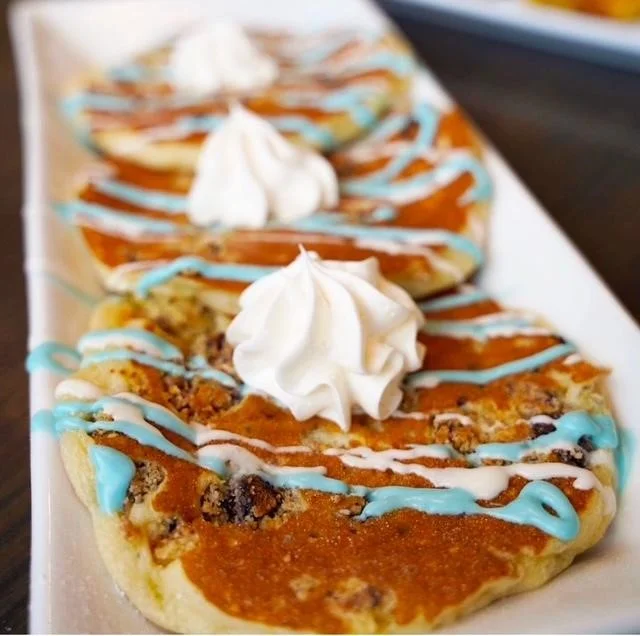 Fluffy pancakes with whipped cream and colorful drizzle