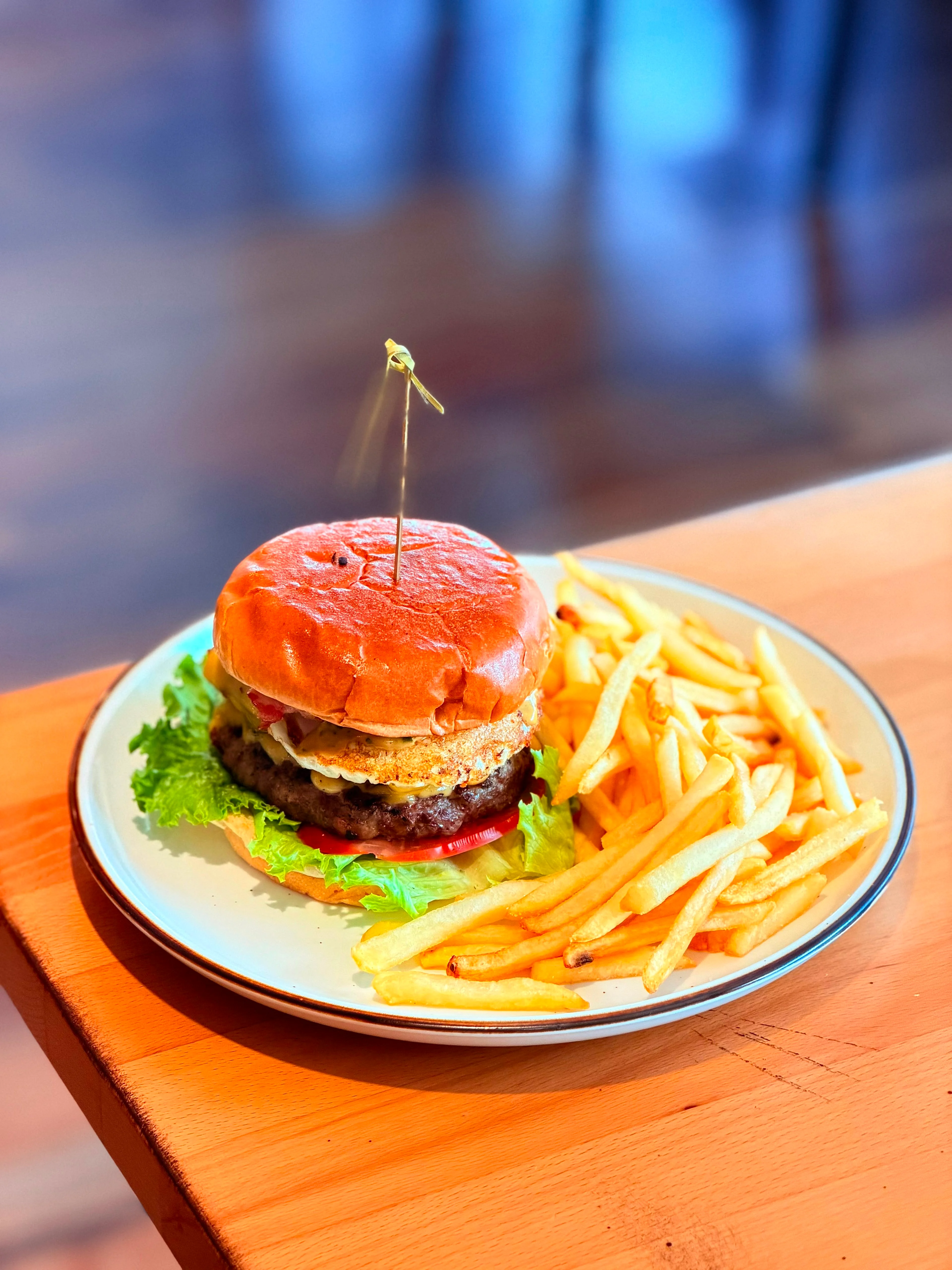 A cheeseburger with a patty, lettuce, and tomato, served with a side of crispy French fries.