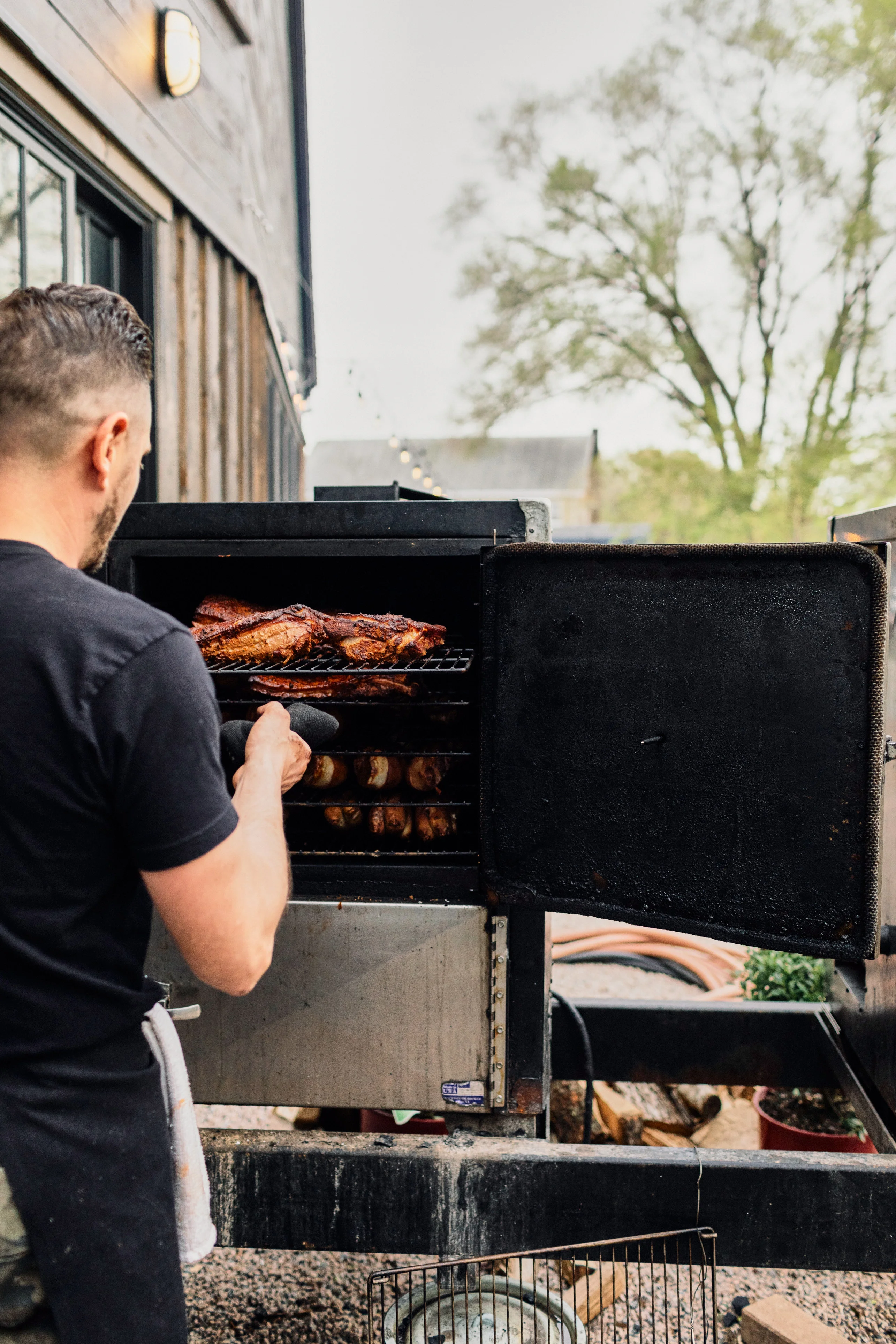 Pitmaster tending to smoked brisket in a barbecue smoker