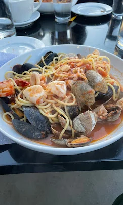 A plate of spaghetti topped with various seafood, including shrimp, mussels, and clams, served in a tomato sauce.