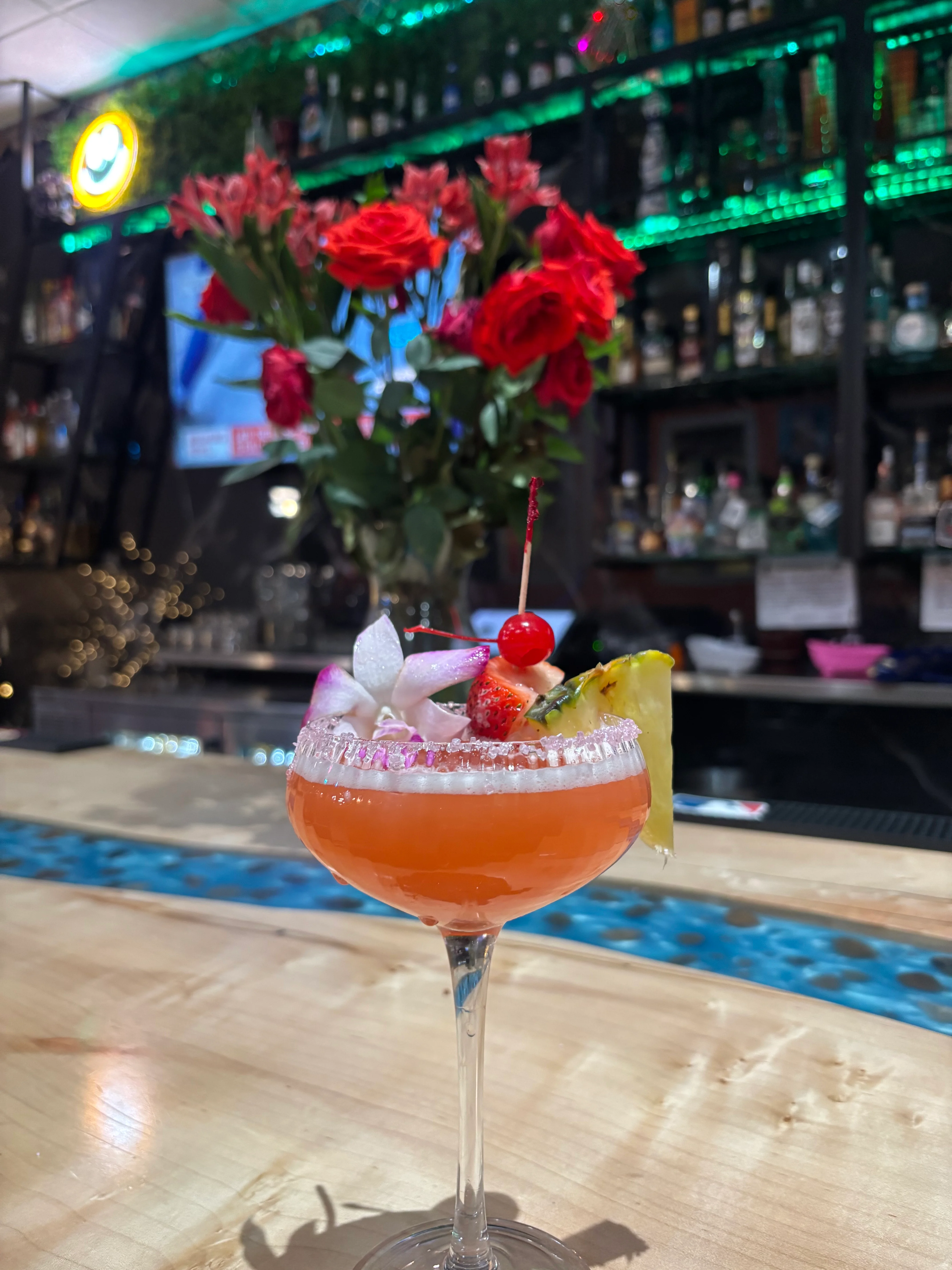 Colorful tropical cocktail garnished with fruit and flowers