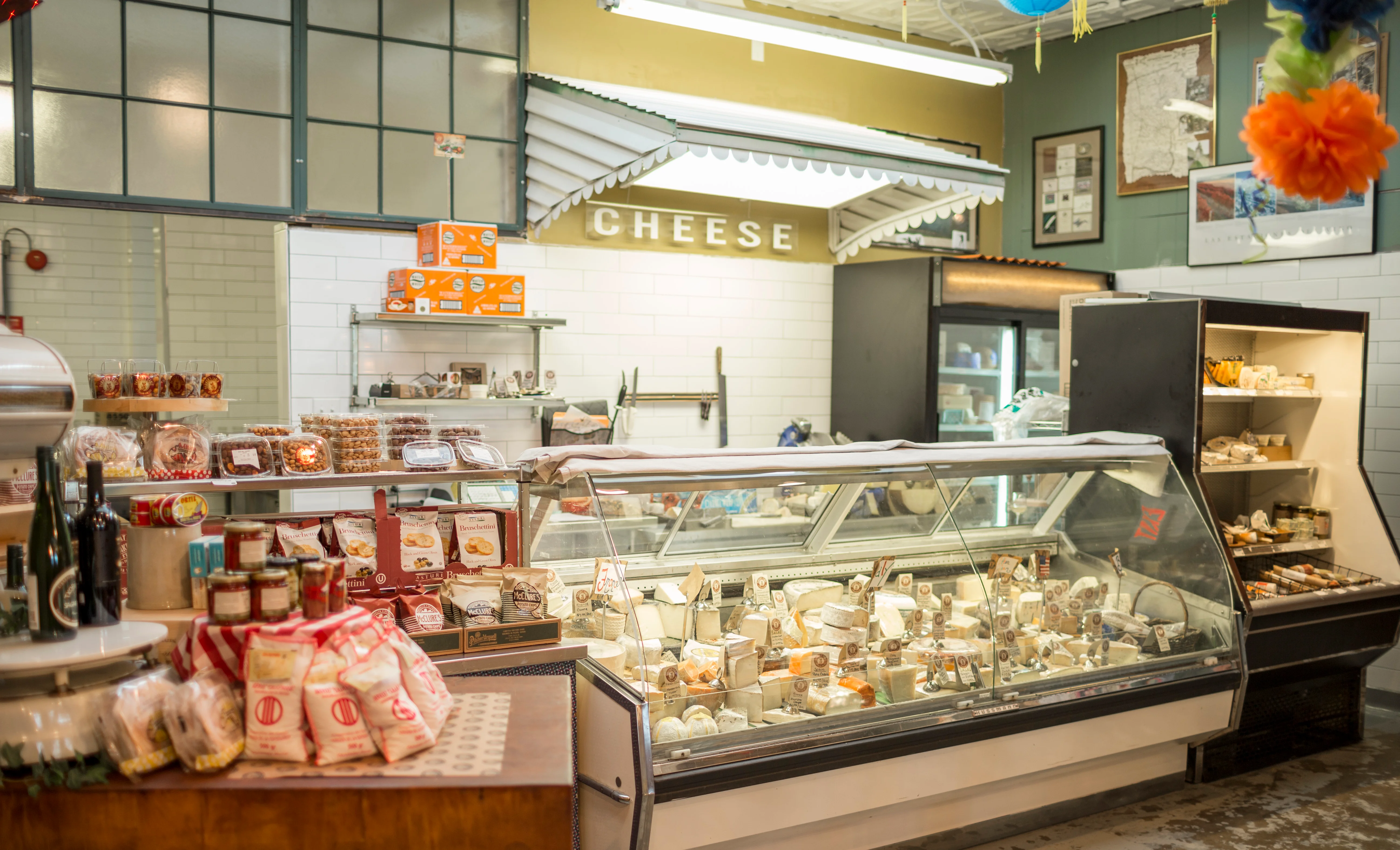 Stacks of wheels of different cheeses from all around the world in our cheese case towards the back of the store by the sandwich station.
