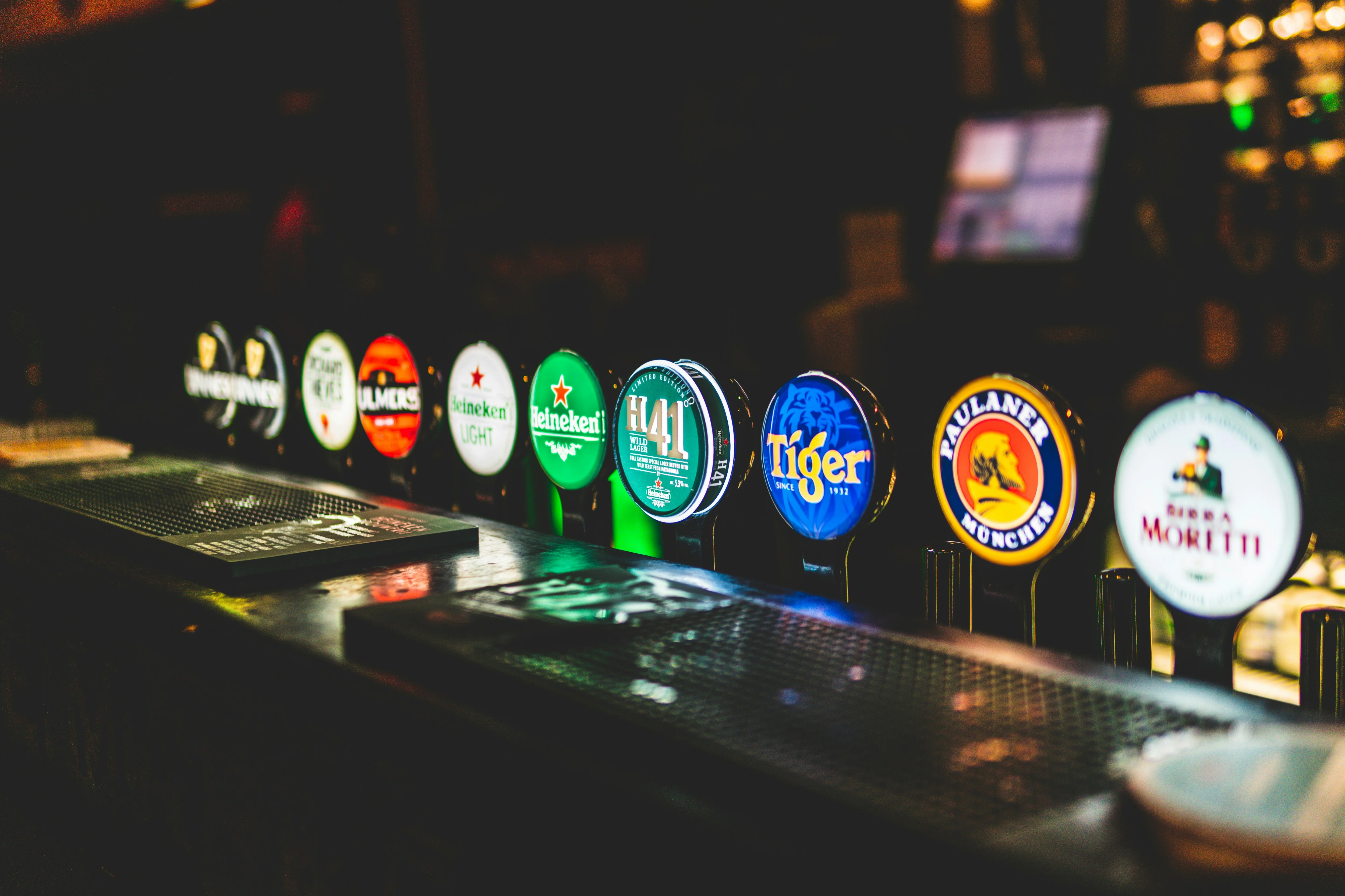 Blurred beer bottles displayed on a dimly lit bar counter